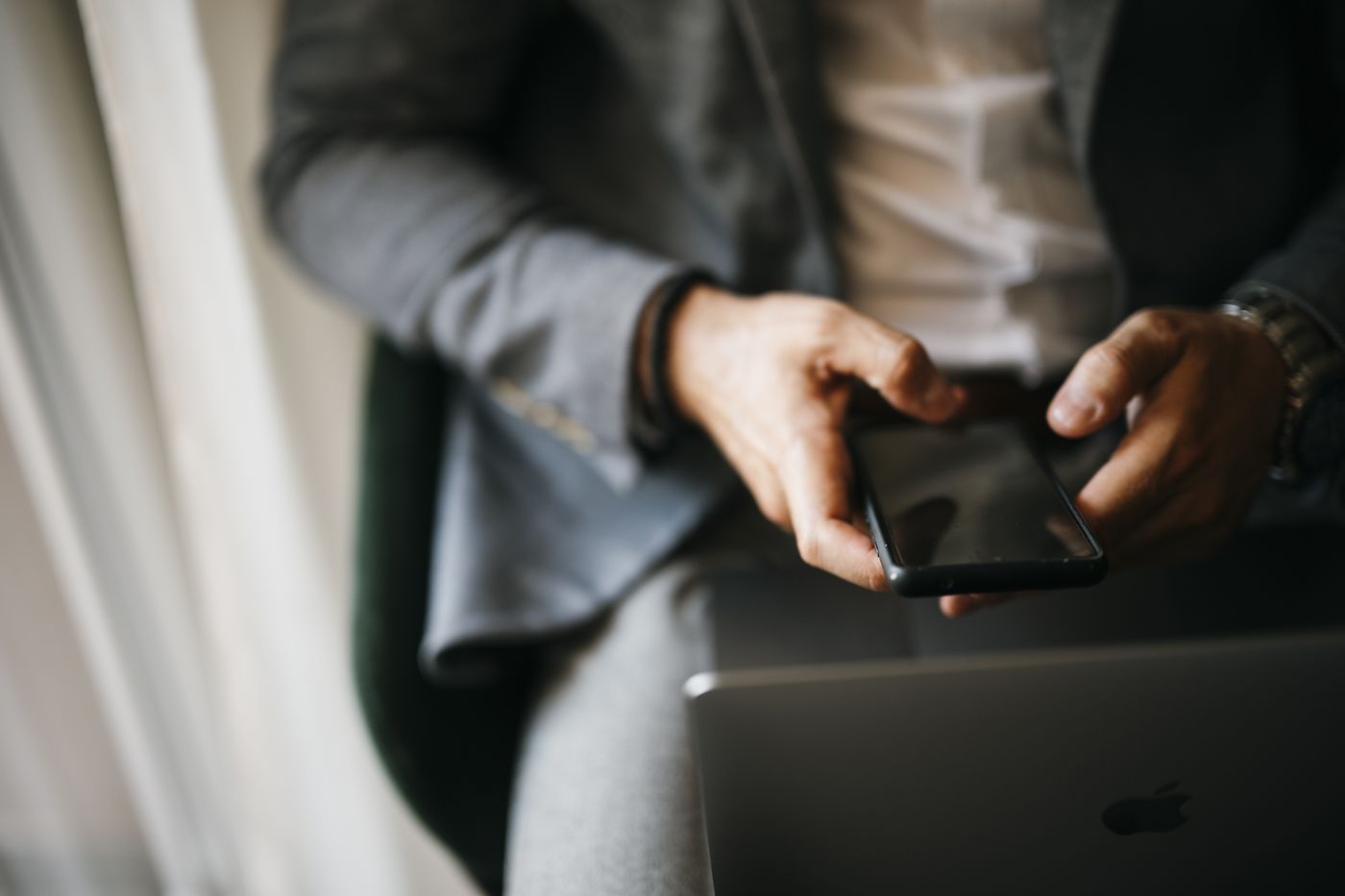 A man in a suit using a phone over a laptop